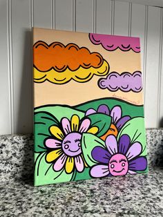 a painting on a counter top with flowers painted on the side and clouds in the background