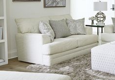 a living room filled with white furniture and lots of pillows on top of it's couches