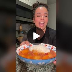 a woman is smiling while holding a bowl of food in front of her face and making a funny face