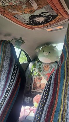 there is a stuffed animal sitting in the back seat of a car with blankets on it