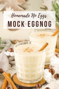 two glasses filled with eggnog on top of a wooden tray next to cinnamon sticks