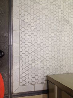 a bathroom with a toilet, sink and shower stall that has hexagonal tiles on the wall