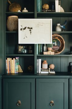 a bookshelf filled with lots of books and vases on top of it