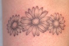 a woman's thigh with three daisies on it