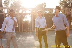 three men standing on a tennis court holding racquets and ball in their hands