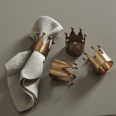 three napkins, one with gold crowns on it and the other has white linen