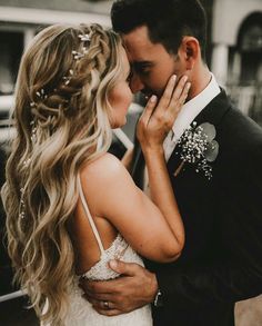 a bride and groom embracing each other in front of a black car on the street