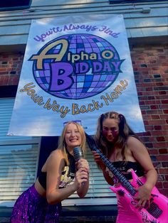 two girls are singing and holding guitars in front of a sign for the 2nd birthday party