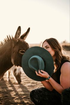 a woman kissing a donkey wearing a green hat