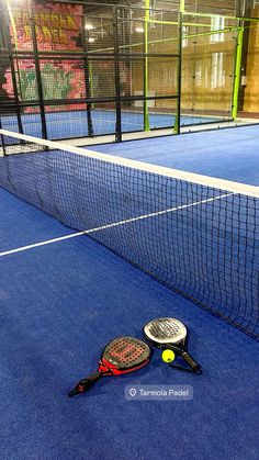 two tennis racquets on the ground next to a net