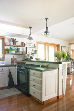 a kitchen with white cabinets and green counter tops on the island in front of an open floor plan