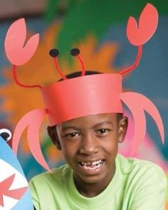 a young boy with a paper hat on his head holding a skateboard in front of him