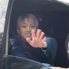 a person in a car waving and holding their hand up to the camera with both hands