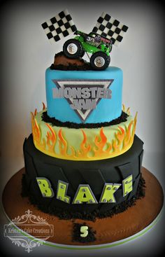 a three tiered cake with a monster truck on top and flames around the edges