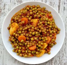 a white bowl filled with peas and carrots