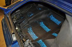 the engine compartment of a blue car with its hood up and some wires in it