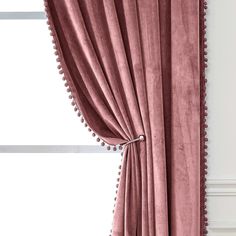 a pink curtain with pom - poms hanging from it's side in front of a window