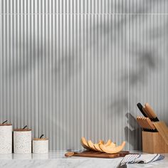 an assortment of kitchen utensils and cutting boards on a countertop next to a gray wall