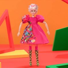 the doll is wearing a pink dress and colorful boots with her hands on her hips