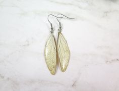 "**LIMITED EDITION** Real cicada wing coated with a few layers of transparent resin. Adorable light translucent real cicada wings resin earrings are lightweight and comfortable to wear. True magic Cicada wings earrings are handmade from natural materials, and slight imperfections are part of the character of the piece. SIZE Earring Hooks length: 10/16\" (16 mm) Resin size: 1/2\" x 1 3/4\" (13 x 40 mm) Colors -clear - Ivory -light green -green -dark green -sky blue -deep blue -red Our earrings ar Pierced Winged Earrings As Gift, Winged Jewelry With Ear Wire For Gifts, White Wing-shaped Earrings For Gift, Cicada Wings, Wings Earrings, Christmas Gift For Women, Transparent Resin, Earrings Resin, Galentines Day