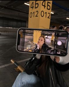 a woman taking a selfie with her cell phone while sitting in a parking garage