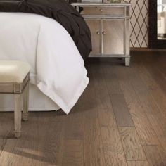 a bedroom with wood floors and white bedding