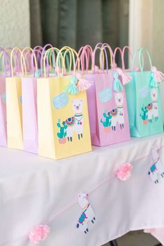 small bags with llamas on them are lined up on a white tablecloth