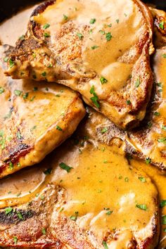 some meat covered in gravy sitting on top of a pan filled with sauce