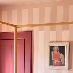 a bedroom with pink and white striped wallpaper, gold bed frame and painting on the wall