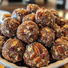 a white bowl filled with chocolate and pecan covered cookies on top of a wooden table