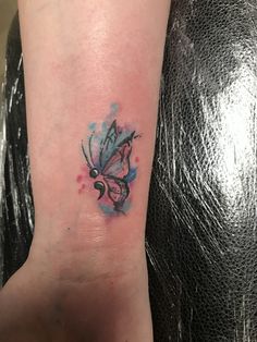 a small butterfly tattoo on the left inner arm and wrist, painted in watercolors