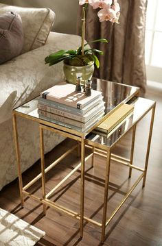 a glass table topped with books and a vase filled with flowers on top of it