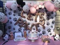 there is a cake and balloons on the table at this birthday party with paw prints