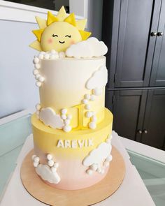 a three tiered cake decorated with clouds and sun