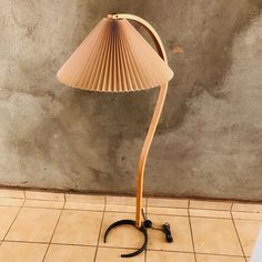 a lamp that is on top of a tile floor next to a wall with a cement background