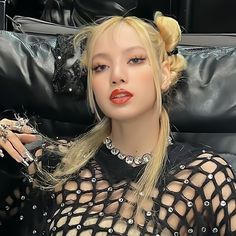 a woman with blonde hair sitting on a black couch wearing a sheer top and diamond jewelry