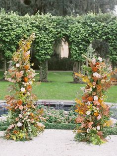 two tall floral arrangements sitting in the middle of a garden