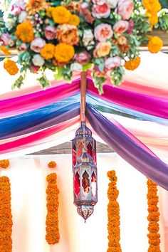 an arrangement of flowers and ribbons decorates the top of a decorated tent for a wedding ceremony