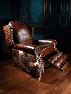 a brown leather chair and foot stool in a room with blue walls, wood floors and wooden flooring