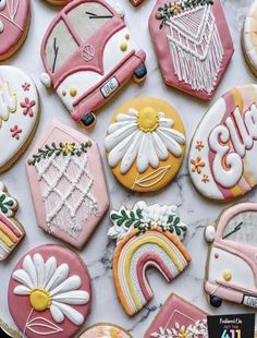 decorated cookies are arranged on a marble countertop with flowers, rainbows and cars