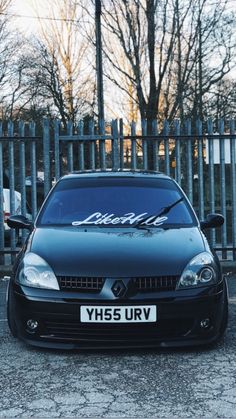 a black car parked in front of a fence