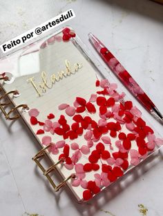 a notepad with red and pink confetti on it next to a pen