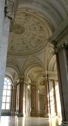 an empty room with columns and arches on the ceiling is pictured in this image, while sunlight shines through the windows onto the floor