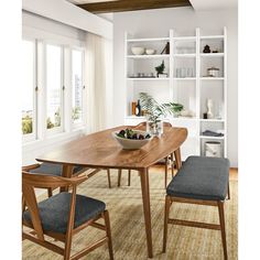 a dining table with two chairs and a bowl of fruit on it in front of open shelves