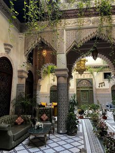 the inside of an ornate building with green furniture and potted plants on either side