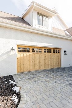 a white brick house with two wooden garage doors