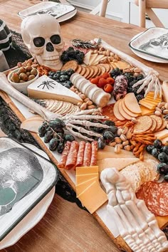 a wooden table topped with lots of cheeses and crackers next to a skull