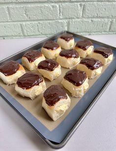 there are many small pastries on the baking pans with chocolate sauce in them