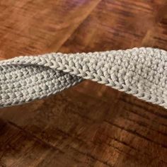 a white knitted tie sitting on top of a wooden table