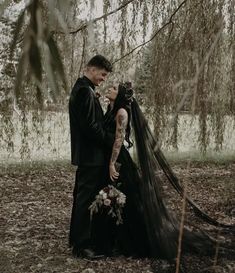 a man and woman standing next to each other under a tree